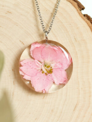 Close-up of August birth flower necklace with flower in resin.