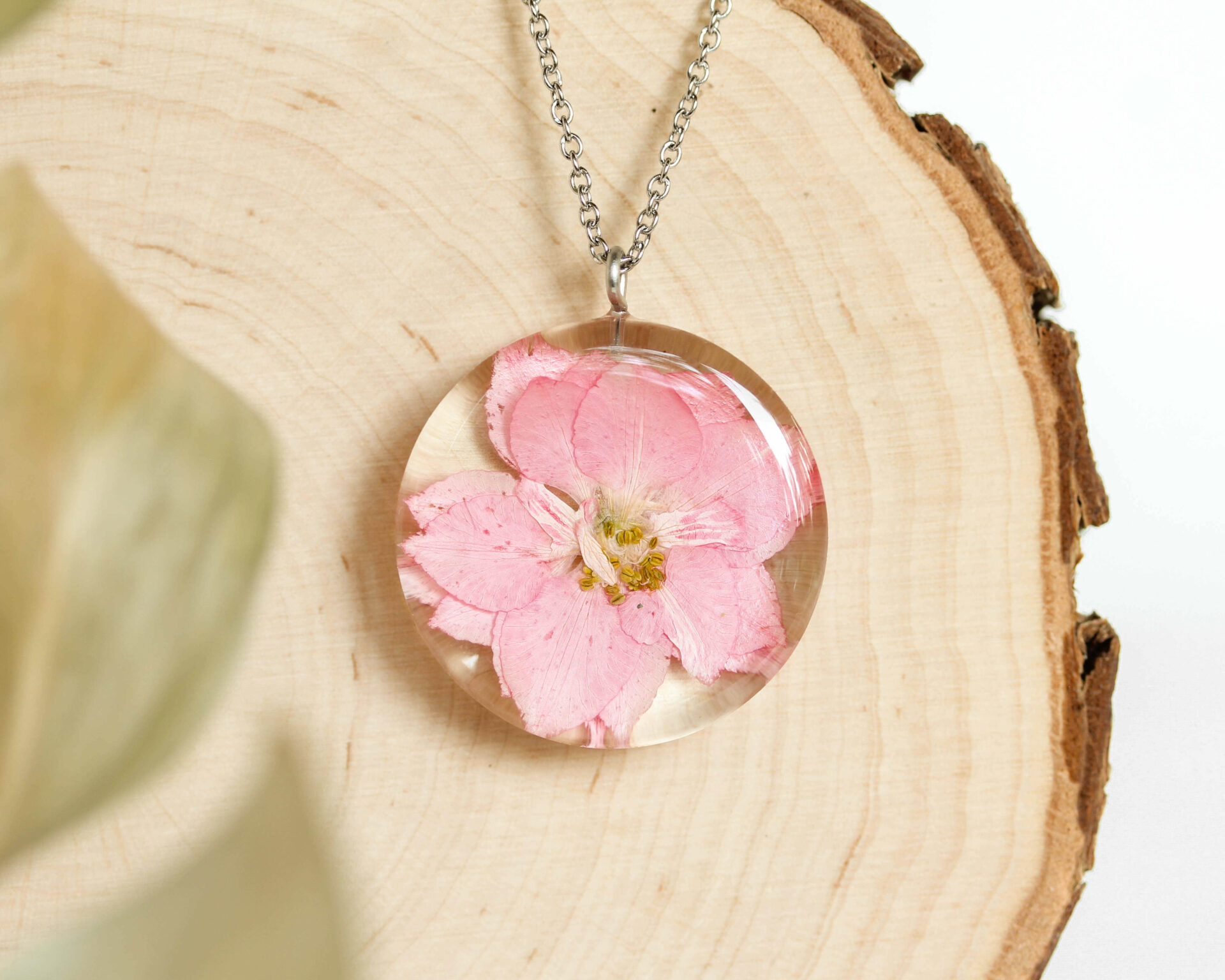 Close-up of August birth flower necklace with flower in resin.