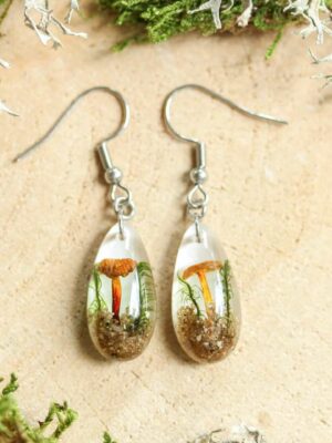 Botanical dangle earrings resembling a miniature forest floor, crafted with tiny mushrooms, sand, and greenery.