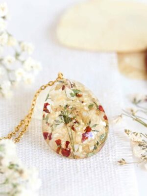 Custom memorial necklace featuring dried funeral flowers embedded in resin, styled on a soft fabric background.