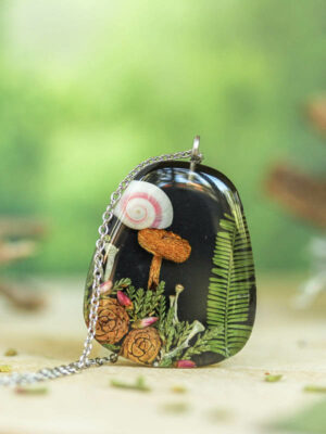 Nature-inspired pendant with botanical elements on wooden background and white lichen