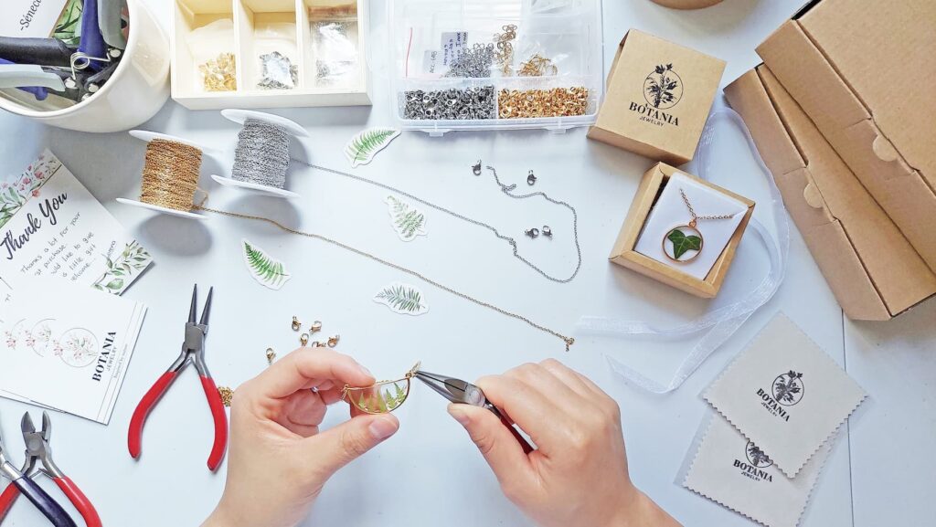 Handmade jewelry assembly and eco-friendly packaging process at Botania Jewelry, featuring fern necklace and branding details